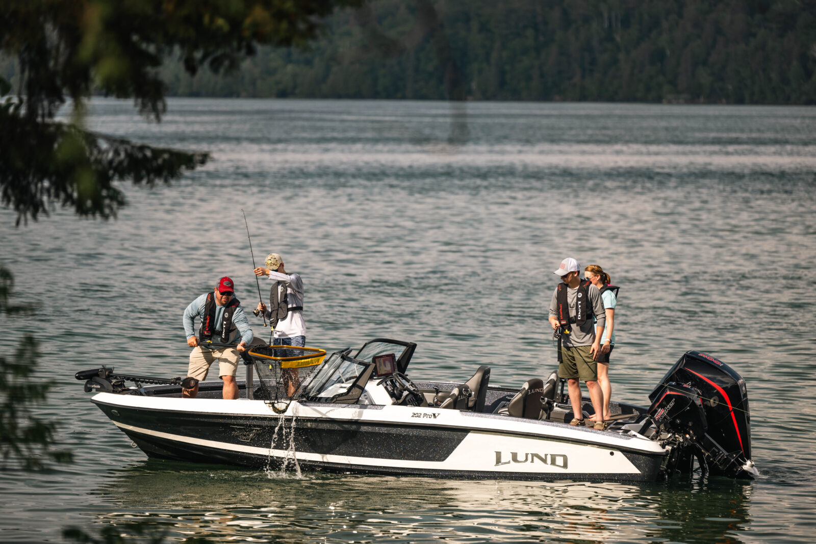 multiple anglers on a boat with a fish in a net